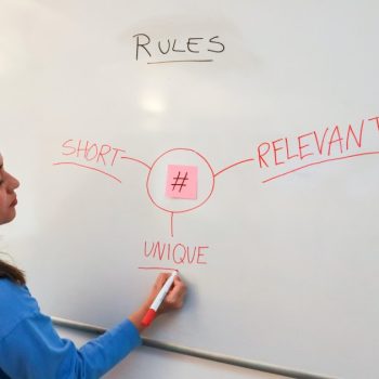 A woman is demonstrating the importance of keywords in front of a whiteboard.