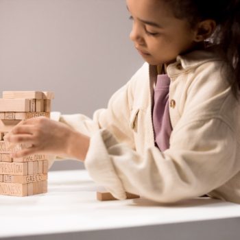 A little girl playing with building blocks on a table
